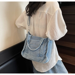 Detail shot of light blue denim tote bag with frayed edges and adjustable shoulder strap