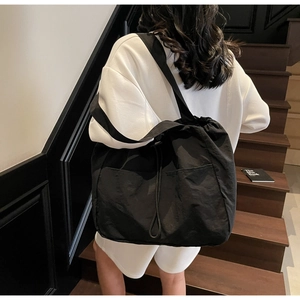 Detail view of a large black waterproof nylon tote bag with drawstring and front pockets