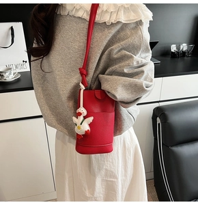 Détail du sac bandoulière rouge texture litchi avec un joli porte-clés canard en peluche