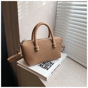 Detailed macro view of caramel woven texture handbag with silver zipper and slim strap