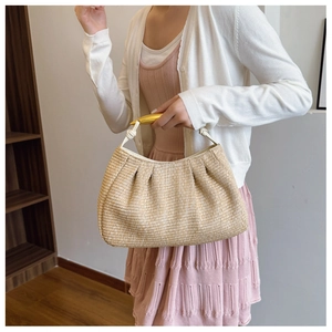 Detail of hand-woven straw bag featuring pleated texture and gold metallic handle