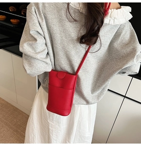 Mini sac bandoulière en cuir rouge à motif litchi porté à l'épaule dans une cuisine