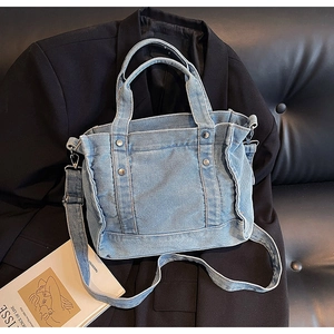 Close-up of light blue denim tote bag with metal rivets and distressed frayed edges