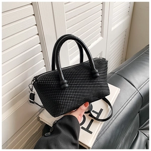 Detail of black woven texture handbag with silver metal hardware and detachable strap