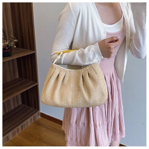 Detail of woven straw bag with golden metal handle and off-white leather trim finish