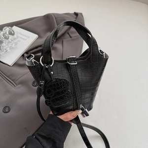 Detail view of black crocodile pattern bucket bag with silver hardware and pendant