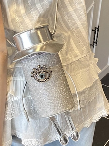 Sparkly silver cylindrical crossbody bag with colorful rhinestone evil eye detail