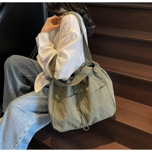 Detail of green nylon drawstring shoulder bag with front pockets on casual outdoor model