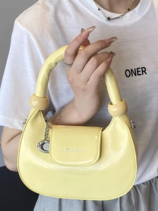 Fashionable yellow crescent handbag in glossy finish with metal handle and chain detail