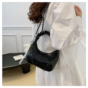Détail du sac sous l'aisselle en cuir verni plissé noir avec chaîne et perles