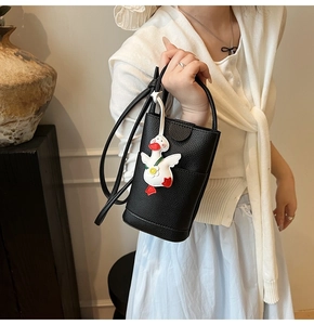 Détail du sac de téléphone en cuir grainé noir avec un charmant pendentif en forme d'oie