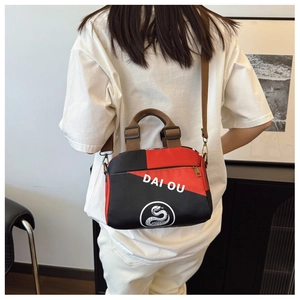 Sac bandoulière rouge et noir avec logo porté à l'épaule par un mannequin