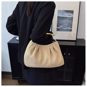 Detailed close-up of straw woven bag with gold metal handle and pleated design