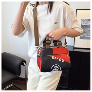 Détail du sac bandoulière en nylon rouge et noir avec logo stylé et sangle marron ajustable
