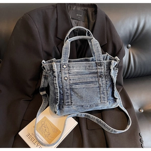 Detailed close-up of blue denim tote bag with vintage metal rivets and stitching detail