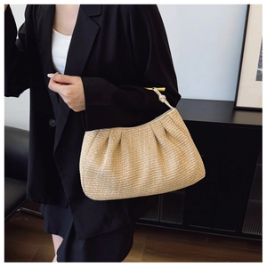 Detail of hand-woven straw cloud bag with elegant gold metal handle and leather strap