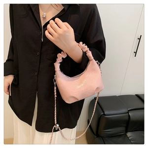Détail d'un sac à main rose avec poignée froncée, cuir craquelé et bandoulière chaîne