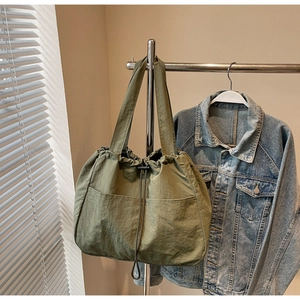 Detail of olive green nylon tote bag featuring front dual pockets and drawstring closure