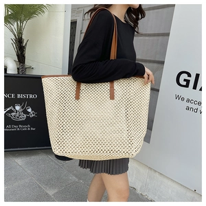 Detail of a large straw tote bag with cream mesh weaving and brown leather straps