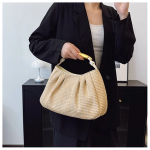 Detailed texture of straw woven shoulder bag with gold metal handle on black blazer