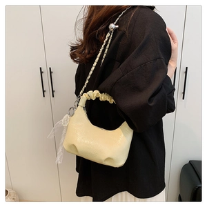 Détail du sac nuage crème avec poignée plissée, chaîne argentée et nœud en dentelle