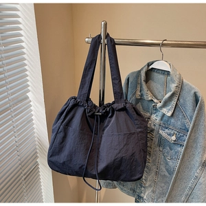 Detail of blue nylon tote bag with drawstring closure and side pockets on a hanger