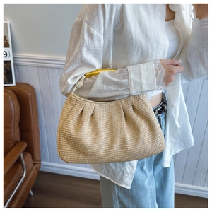 Detailed view of handmade straw handbag with golden metal handle and white knot strap