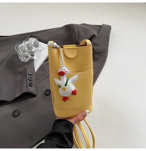 Gros plan du sac de téléphone en cuir grainé jaune avec un pendentif canard mignon