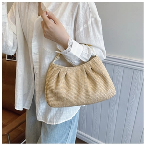 Detail of a beige woven straw bag with cloud-like pleats and natural texture design