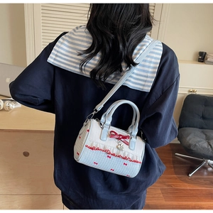 Blue and white Boston bag with red ribbon worn as a crossbody bag by a model