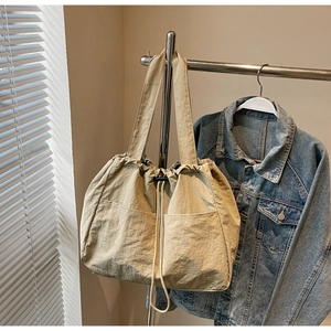 Detail of waterproof nylon drawstring tote bag with dual front pockets and ruched texture