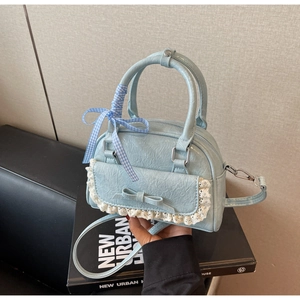 Detail der hellblauen Schleifenhandtasche mit Spitzenbesatz und kariertem Band am Griff