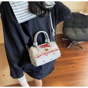 Detail view of cream Boston bag with red bow prints and lace trim shown in a cozy setting