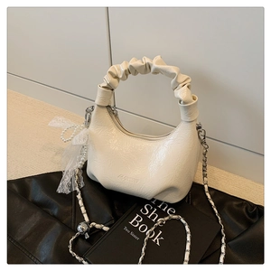 Détail du sac nuage blanc crème en cuir verni brillant avec poignée plissée et nœud en dentelle