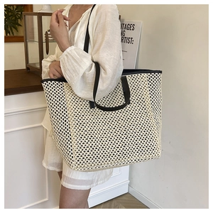 Detail of a large woven straw tote bag with black faux leather straps for beach holidays