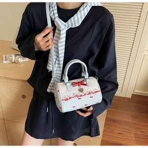 Detail view of a light blue Boston bag with red bows, lace trim, and heart pendant decoration