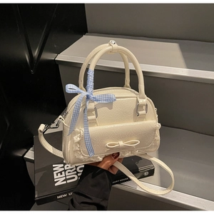 Detail der cremeweißen Faltenledertasche mit Spitze und blau karierter Schleife
