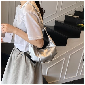 Detail view of silver dumpling bag featuring pleated metallic texture and metal ball knot