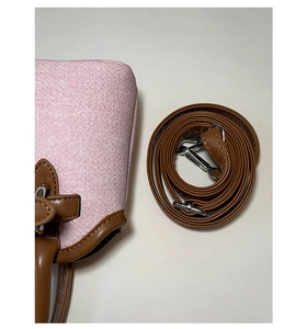 Detailed macro view of pink fabric texture and brown leather strap with metal hook