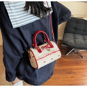 Close-up of cream Boston bag with red bow prints and heart pendant on a casual model outfit