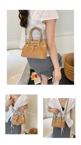 Detailed view of straw-woven crossbody bag with brown leather handles and removable strap