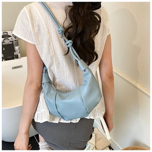 Detail of light blue pleated hobo bag featuring unique double knot shoulder strap design