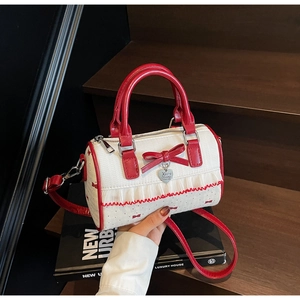 Detailed close-up of a white polka dot Boston bag with red bow and heart charm