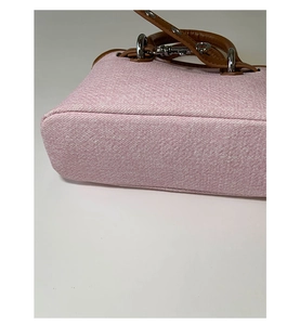 Close-up of pink tweed shell bag featuring brown leather straps and silver metal hardware