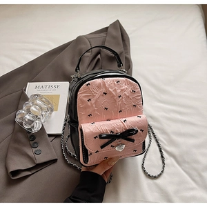 Detail of pink puckered fabric and black bow prints on stylish mini backpack