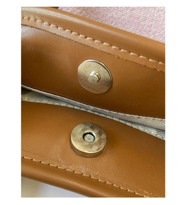 Detailed macro view of high-quality double magnetic closures on a brown leather handbag