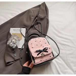 Detail of pink mini backpack with 3D embossed hearts, black bows and heart pendant charm