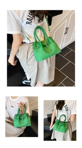 Detail of green woven bucket bag showing its leather handle and textured stripe pattern