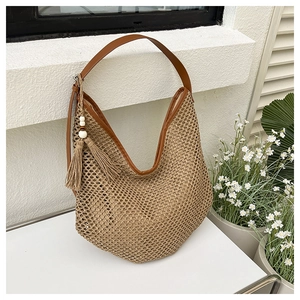 Detail of straw shoulder bag featuring side tassels, wooden beads, and brown leather straps