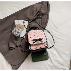 Detail of pink bow pattern seersucker backpack with heart pendant and metal chain